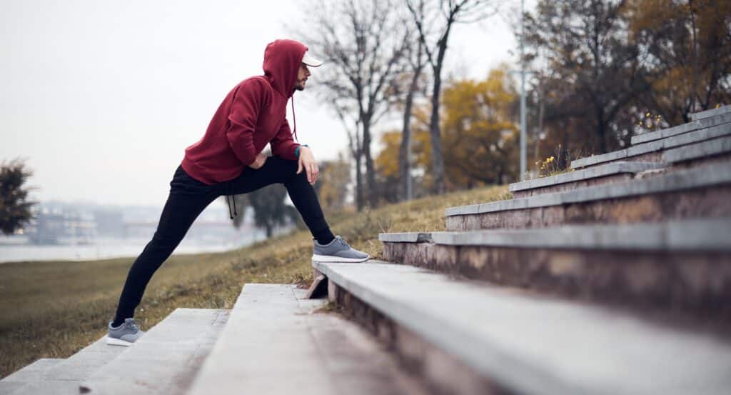Sportler dehnt Beine an Treppe im Park | Elf Bar Vape